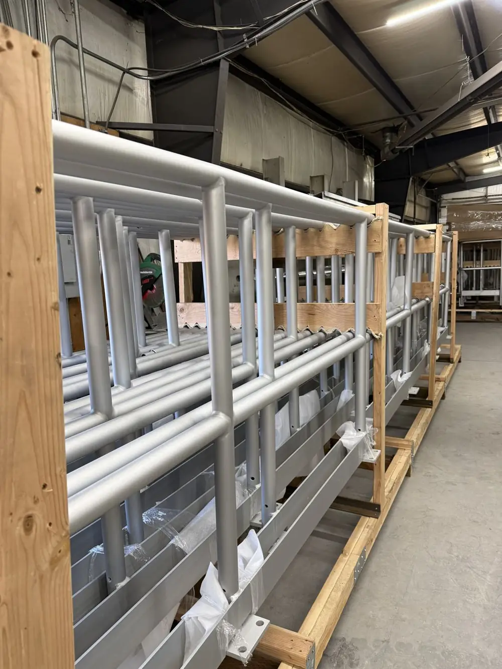 Finished aluminum guardrail panels held apart from each other inside a purpose-built timber shipping crate