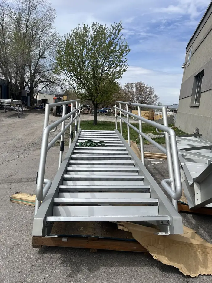 A finished aluminum stair with guardrail staged outside the shop