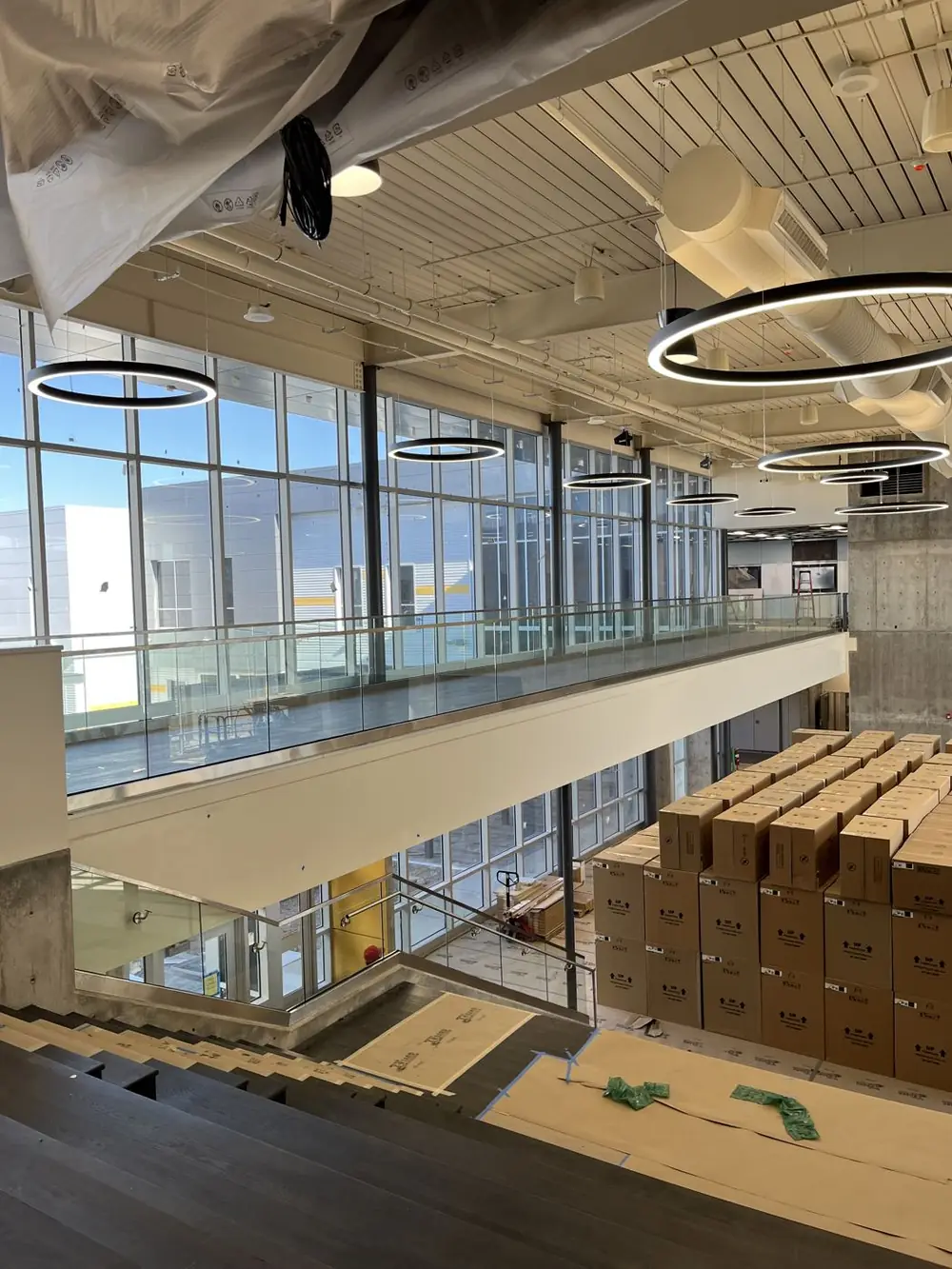 Looking down over the glass guardrail at the mezzanine edge to the commons floor below