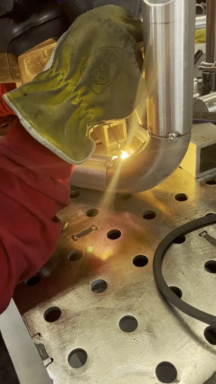 Close view through a welding hood lens as an arc strikes a bronze component