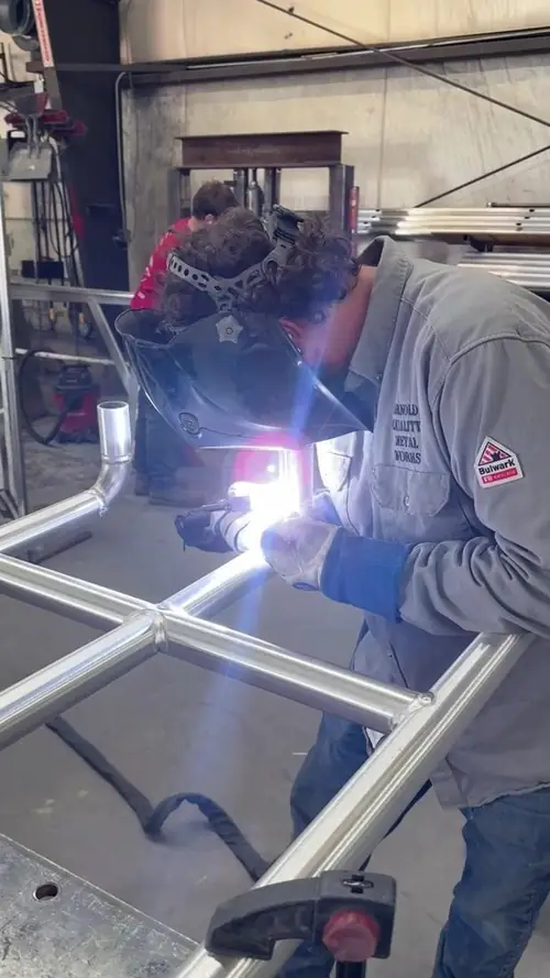 A welder running an arc on an aluminum frame assembly