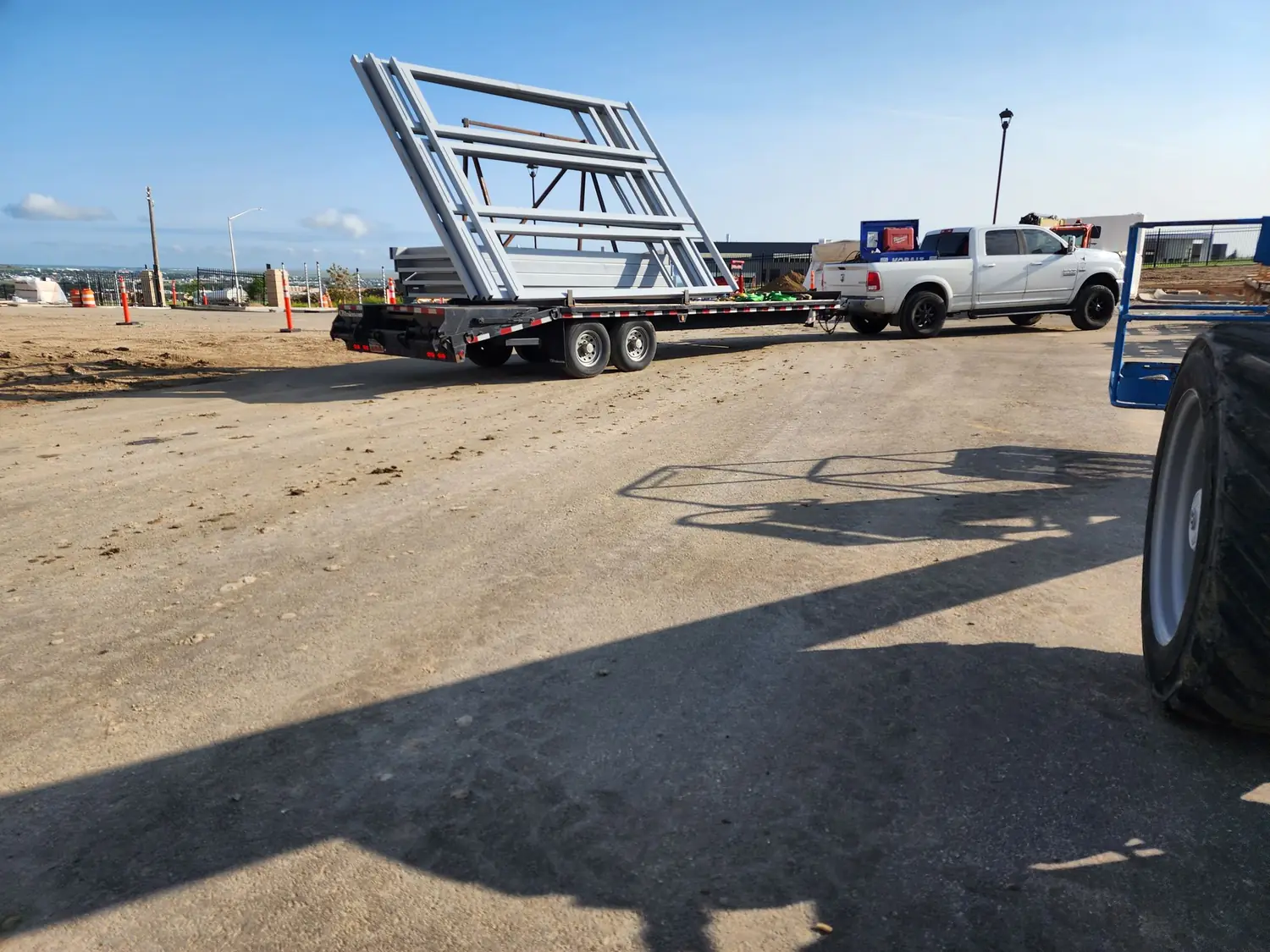 Window frame assemblies strapped upright to a gooseneck trailer at the jobsite under an open Wyoming sky