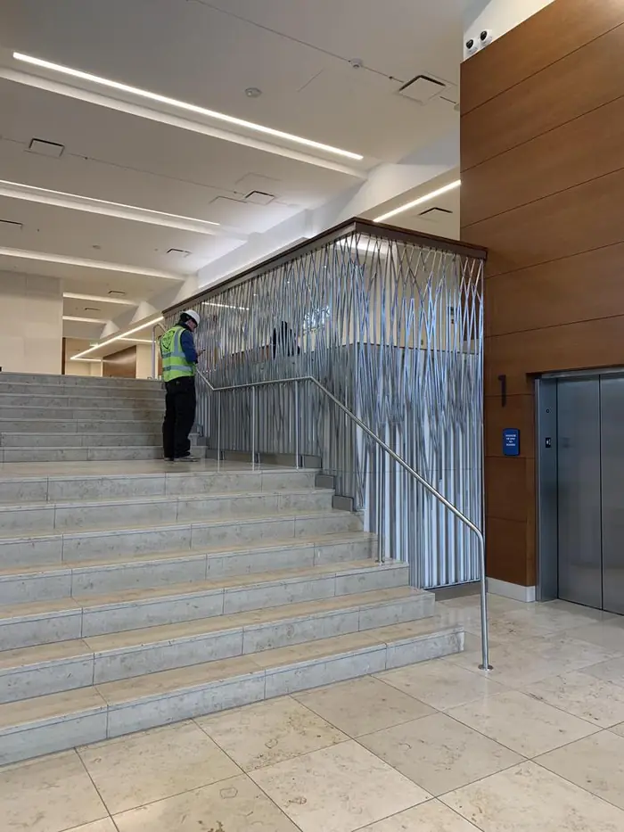 Crew member working at the top of the stair alongside the installed grass-motif panel