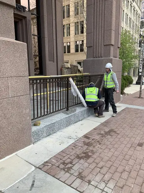 Crew installing powdercoated aluminum guardrail against the granite facade outside at City Creek