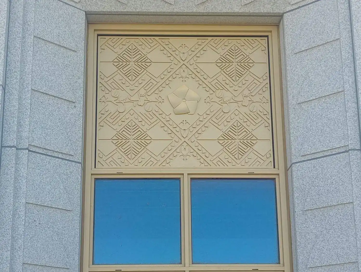A finished decorative transom panel set in the cast stone facade above a temple window at Elko