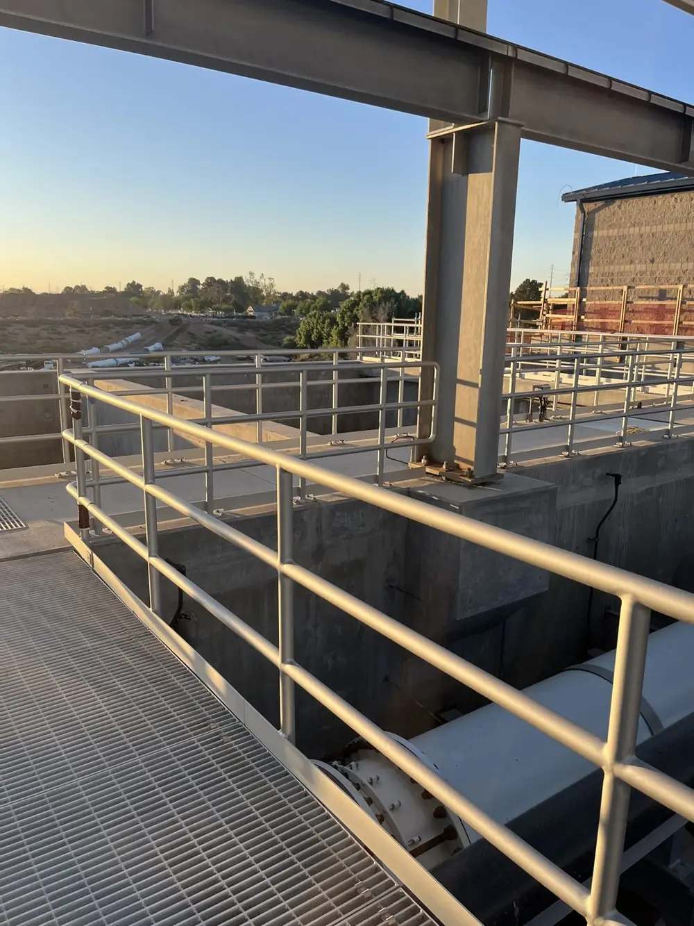 Anodized aluminum guardrail running along the edge of a concrete basin at the Gilbert water treatment plant in late afternoon light