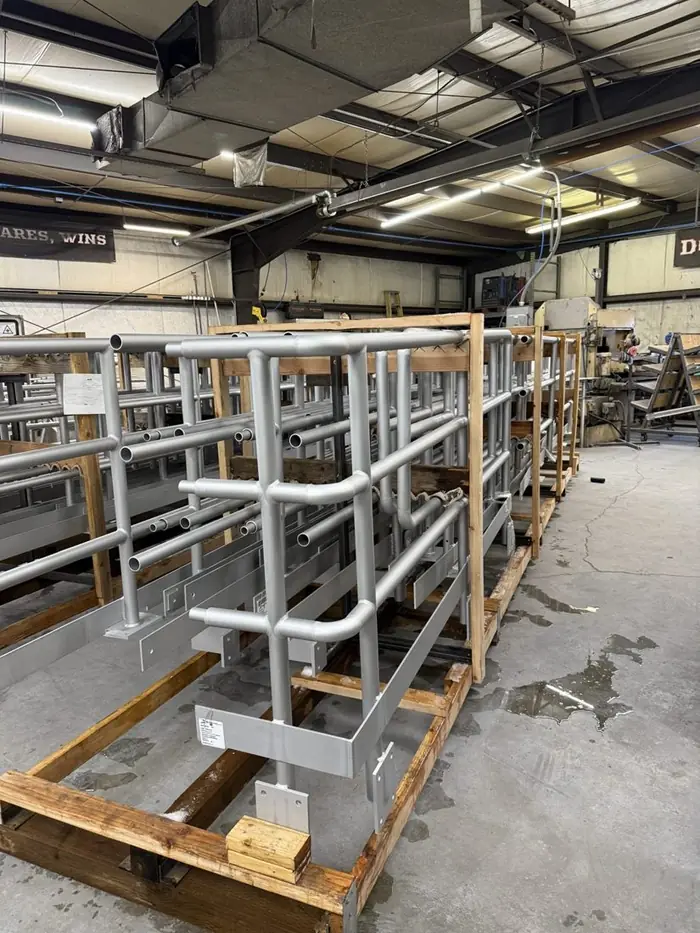Crated anodized aluminum guardrail assemblies stacked on shipping frames in the Arnold Quality shop