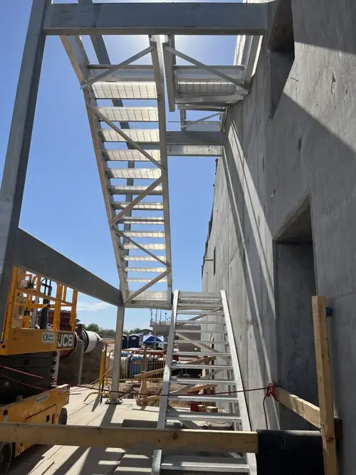 Anodized aluminum stair running down a concrete wall at the plant during construction