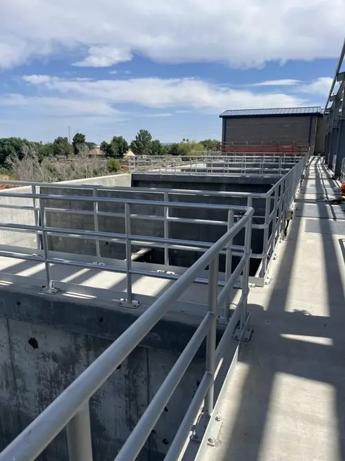Guardrail running the full length of a concrete basin wall at the plant