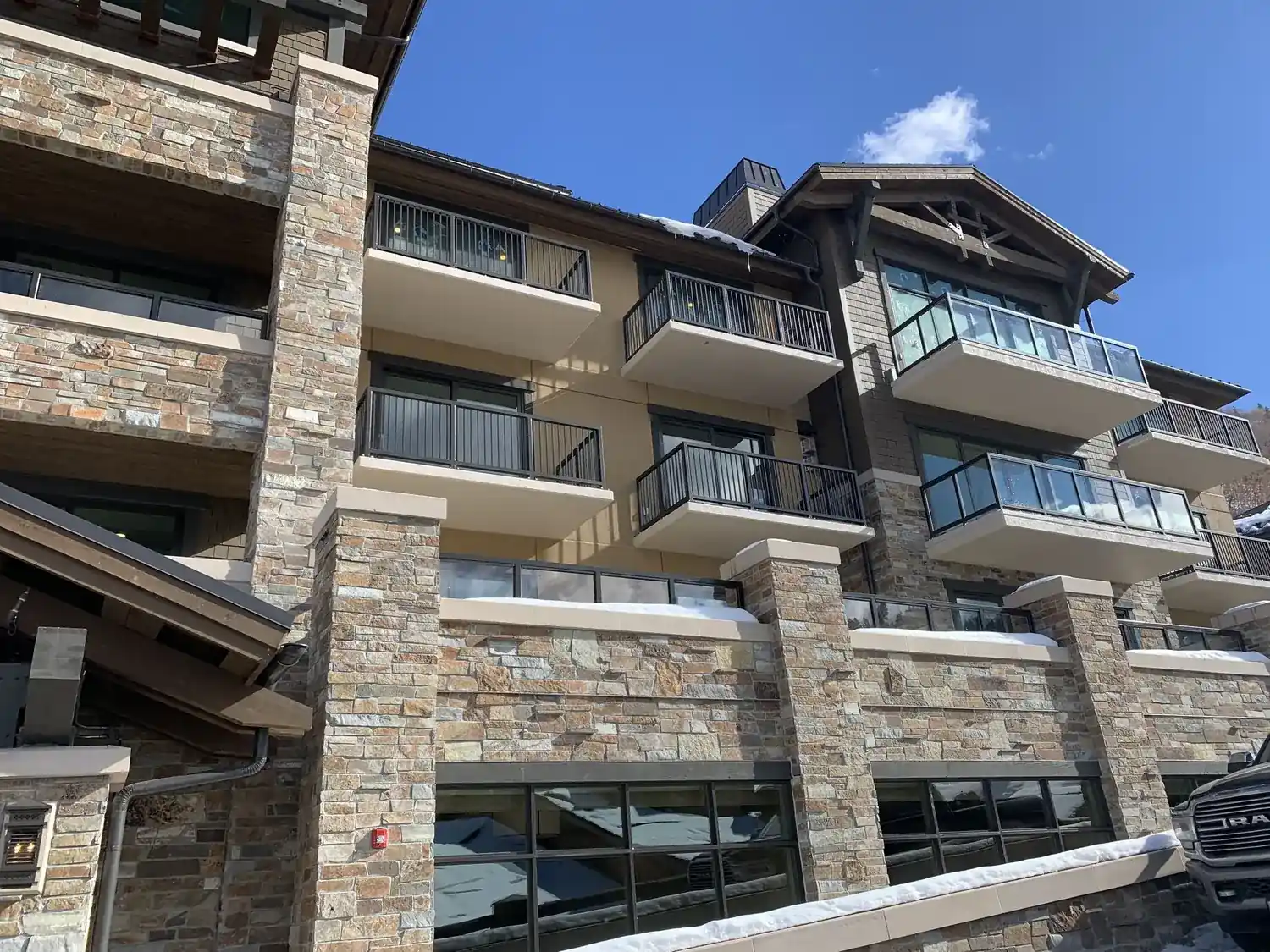 Glass infill balcony guardrail across the face of a stone and timber resort building