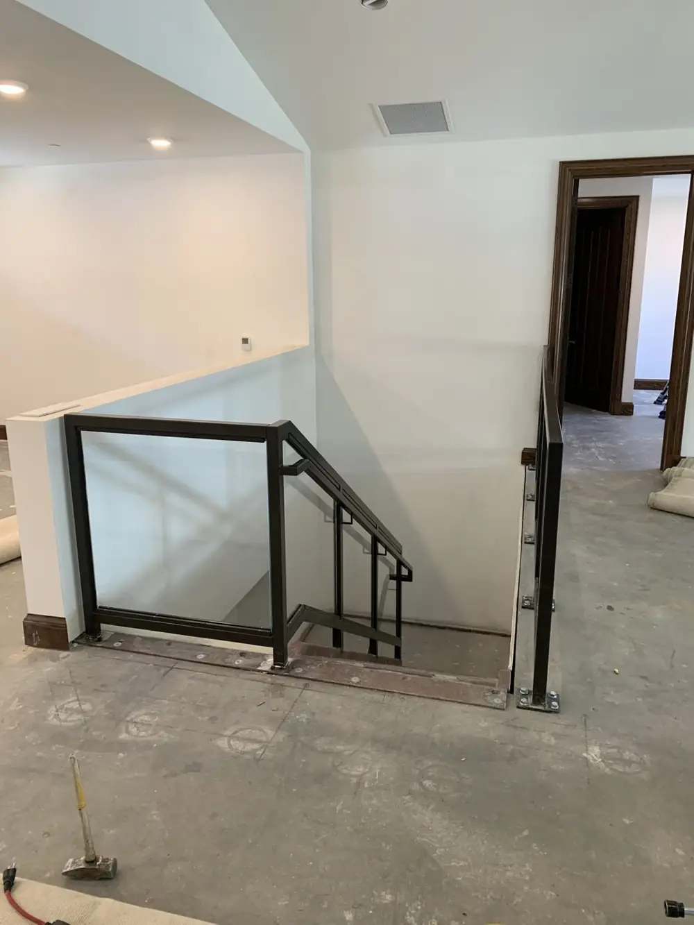 Glass infill guardrail at an interior stair opening in a finished residence