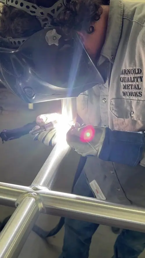 A welder laying a TIG bead on an aluminum rail joint, hood down