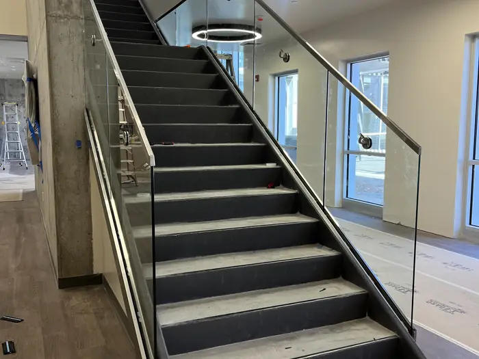 Glass guardrail with a stainless cap rail running up a finished interior stair