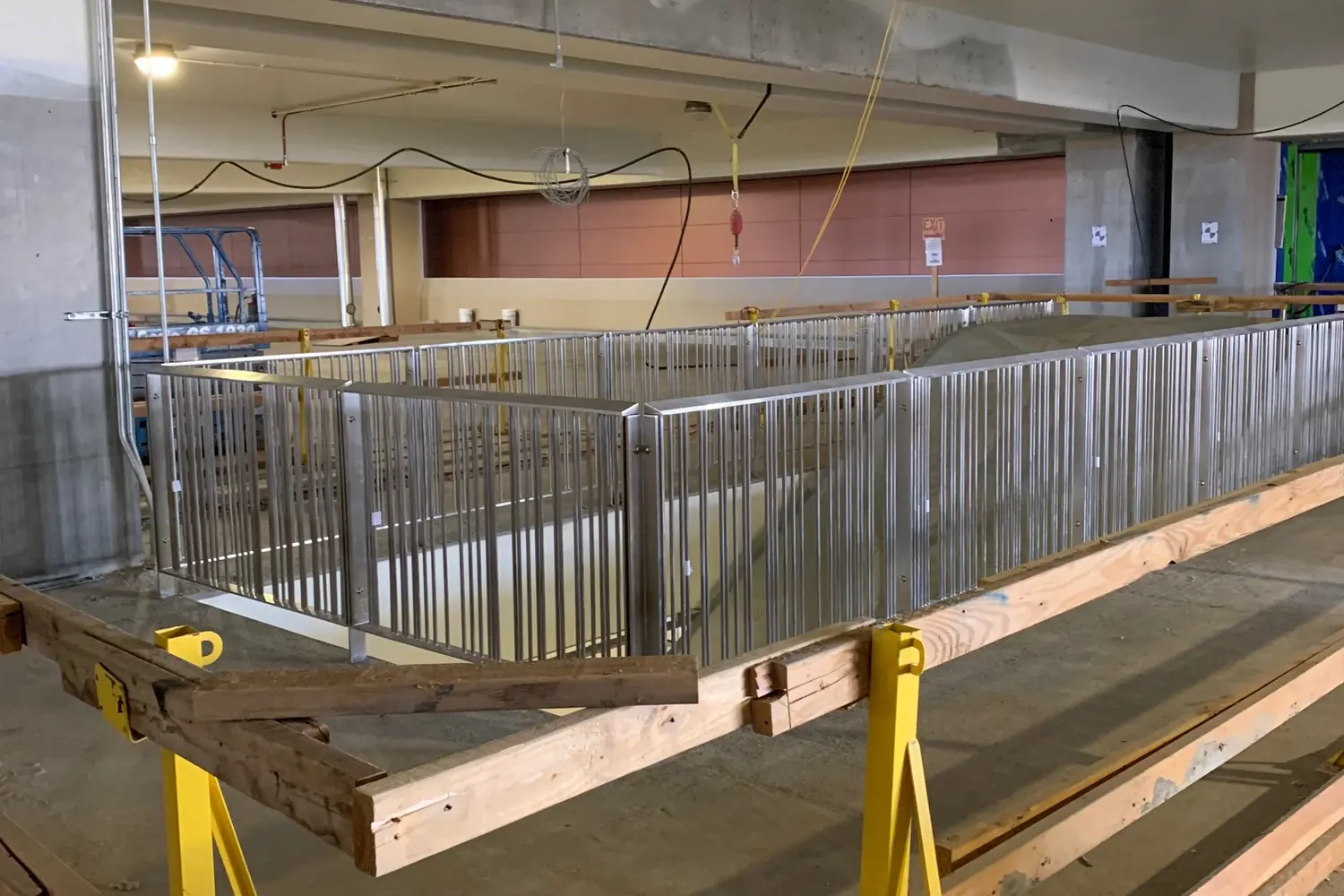 Long stainless guardrail panels resting on sawhorses across an open fabrication bay