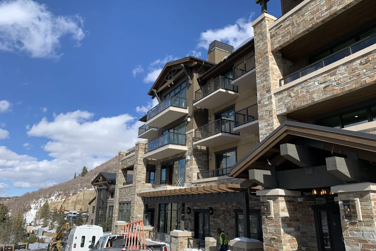 Glass infill balcony guardrail across the face of a stone and timber resort building