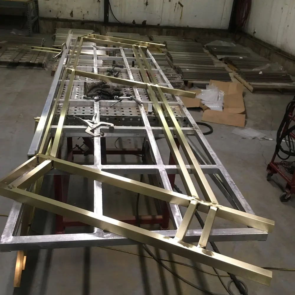 Architectural bronze frame sections laid out across a fabrication table