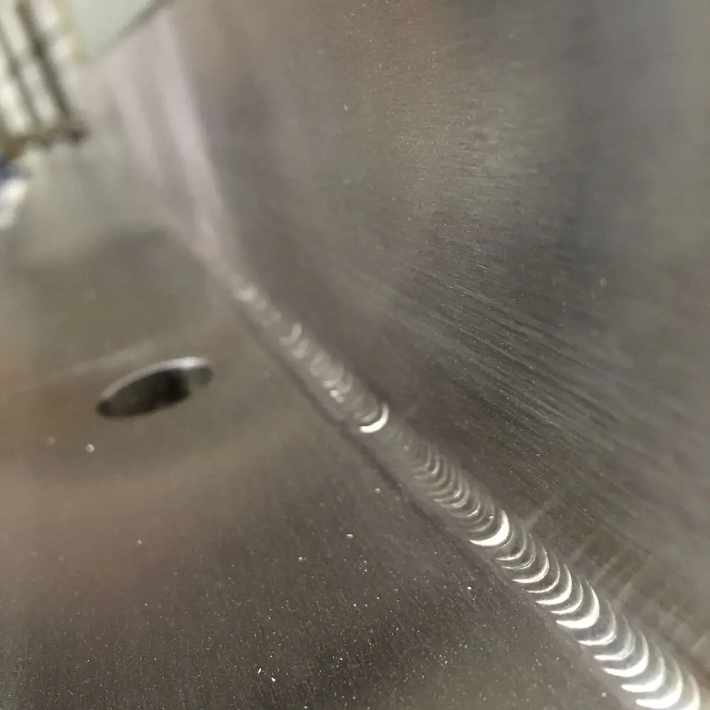 Close view of a finished weld bead on stainless before the surrounding surface is re-grained