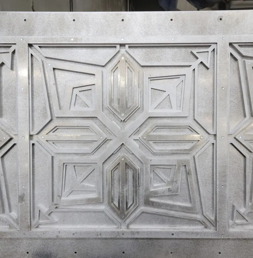 A layered laser-cut aluminum panel in bare metal before finishing