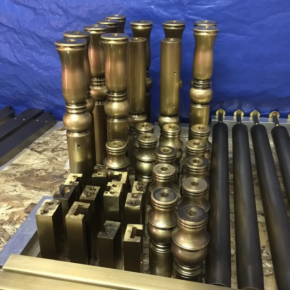 Turned bronze newel components and rail stock staged in the shop during the takeover