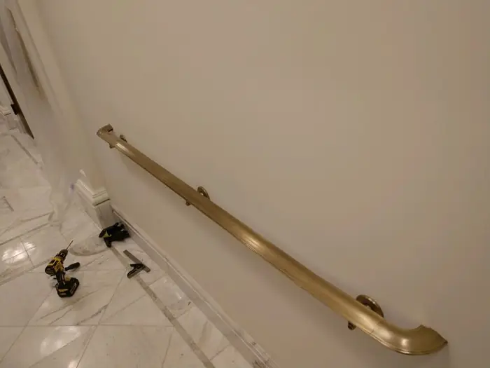 Wall-mounted bronze handrail installed on a finished interior wall