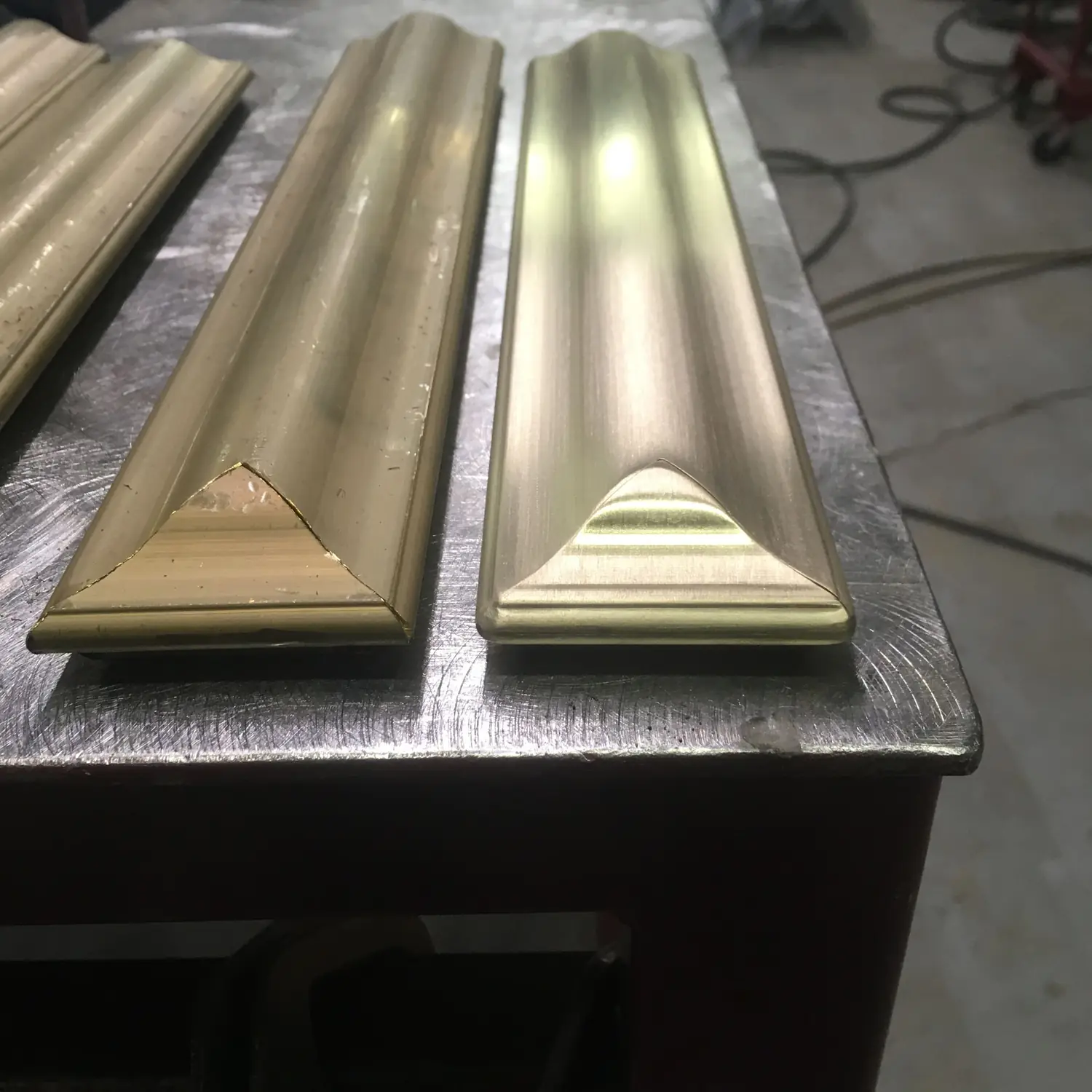 Two profiled architectural bronze cap rails on the bench, mitred ends and brushed surface