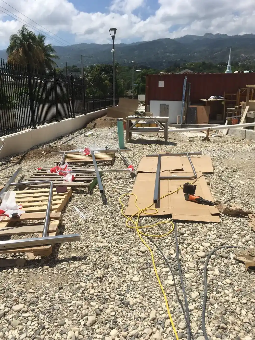 Rail sections laid out for fitting on the temple site in Port-au-Prince, with the surrounding hillside beyond