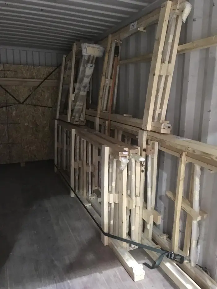 Crated and braced rail assemblies loaded inside a shipping container for transit