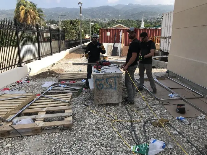 Crew cutting and fitting rail sections on the temple site in Port-au-Prince