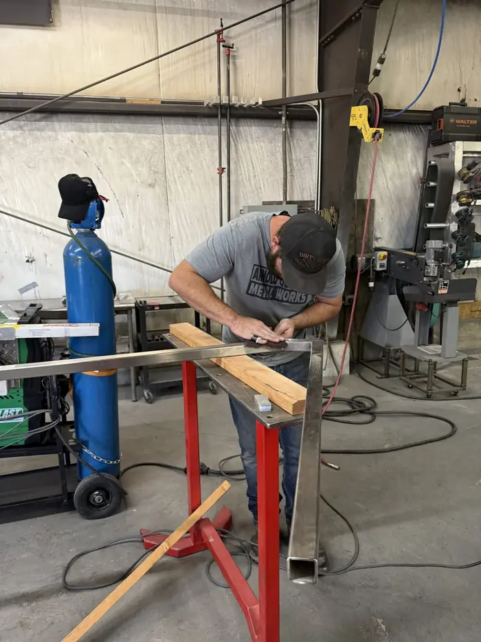 A fabricator marking and measuring an aluminum section at the bench before cutting