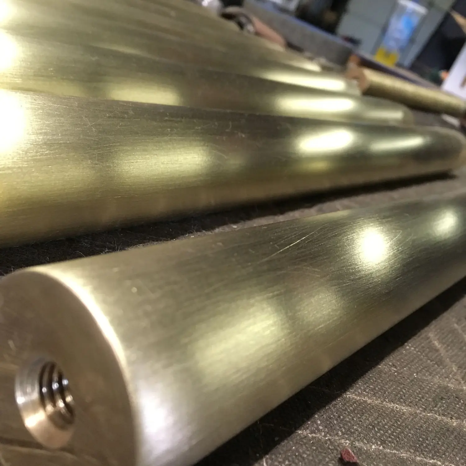 Brushed architectural bronze cap rail sections in raking light on the shop floor