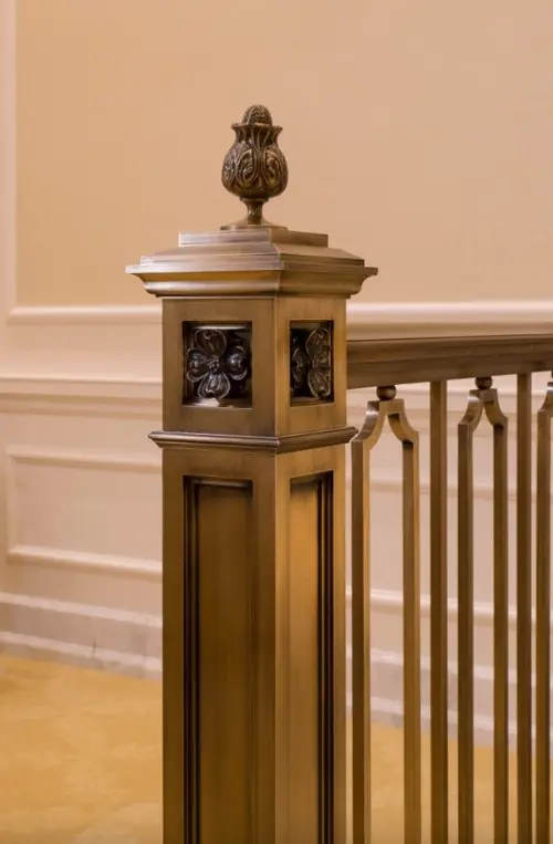 Finished bronze newel post at Raleigh showing the flower motif worked into the panel detail