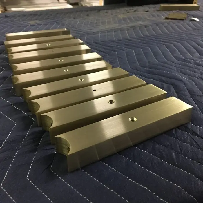 Extruded bronze cap rail sections laid out and brushed in the shop
