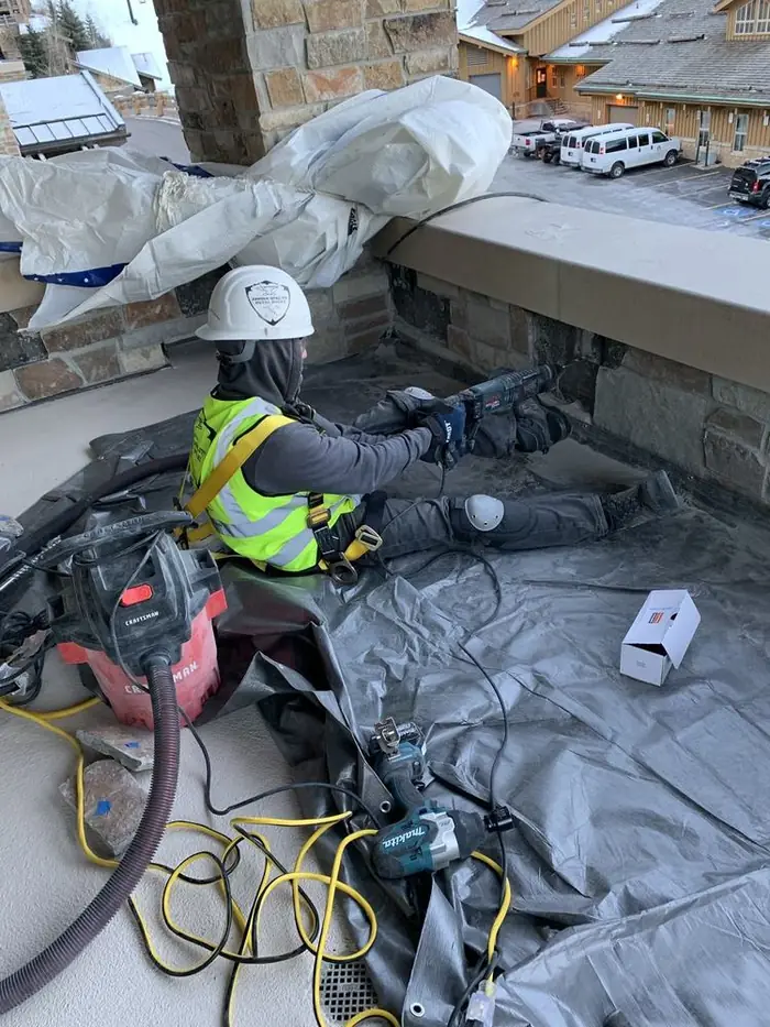 Crew member working beneath a balcony in deep snow during the winter installation
