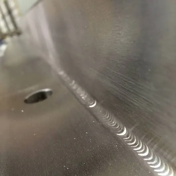 Macro photograph of a uniform TIG weld bead running into a radiused stainless transition