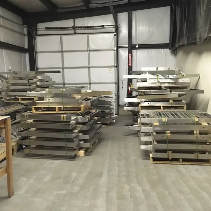 Completed stainless rail assemblies stacked on pallets across the Arnold Quality shop floor