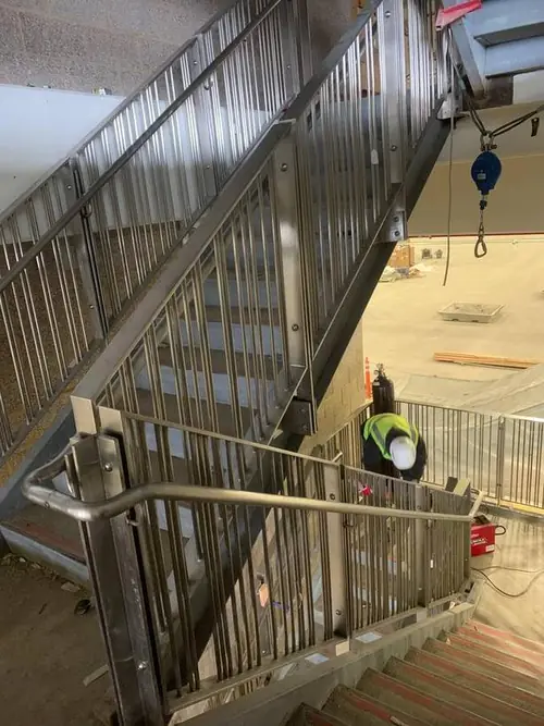 Stainless guardrail and handrail installed on a stair run during construction