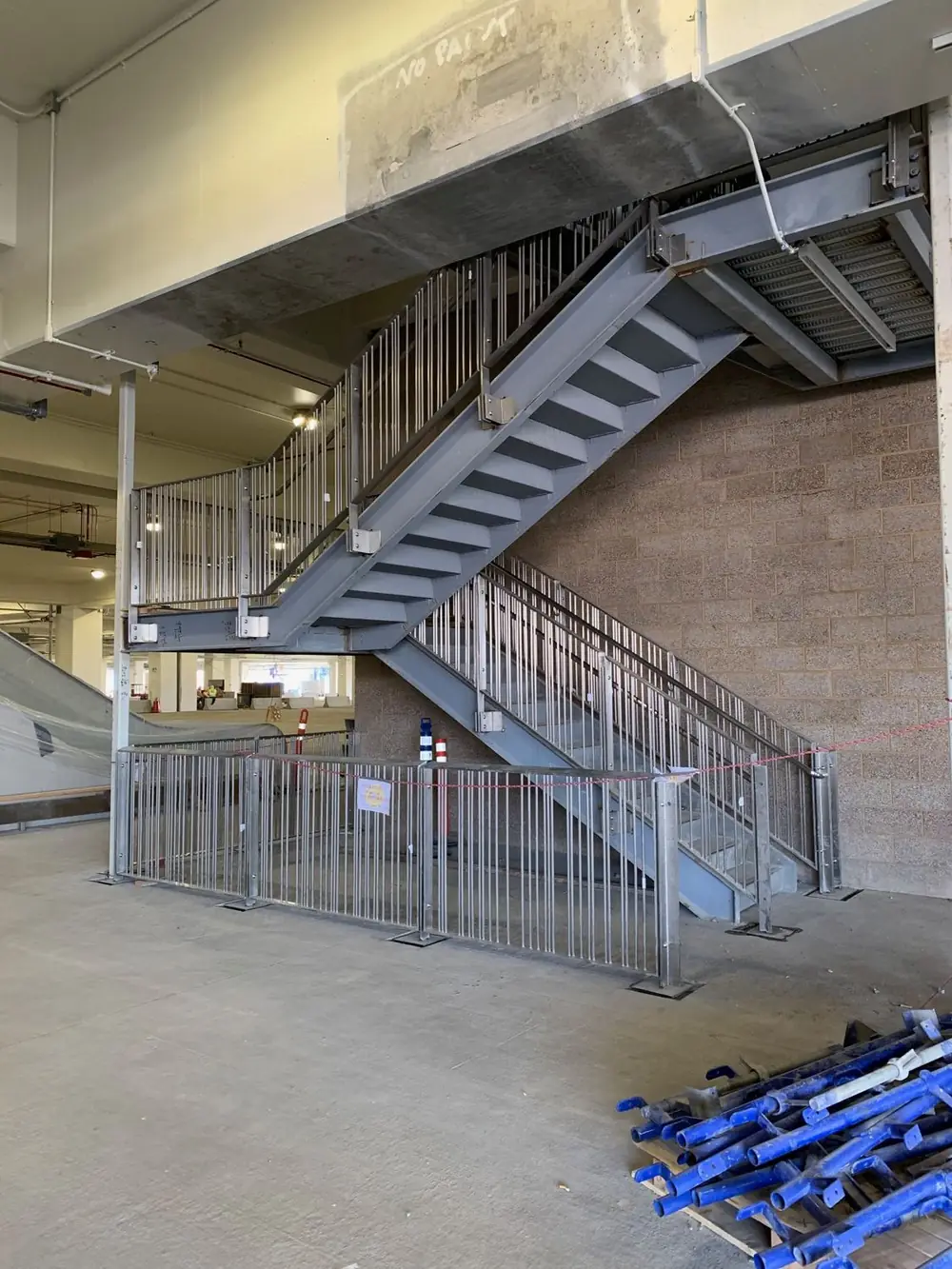 A long run of stainless guardrail and handrail descending a stair in a concrete structure