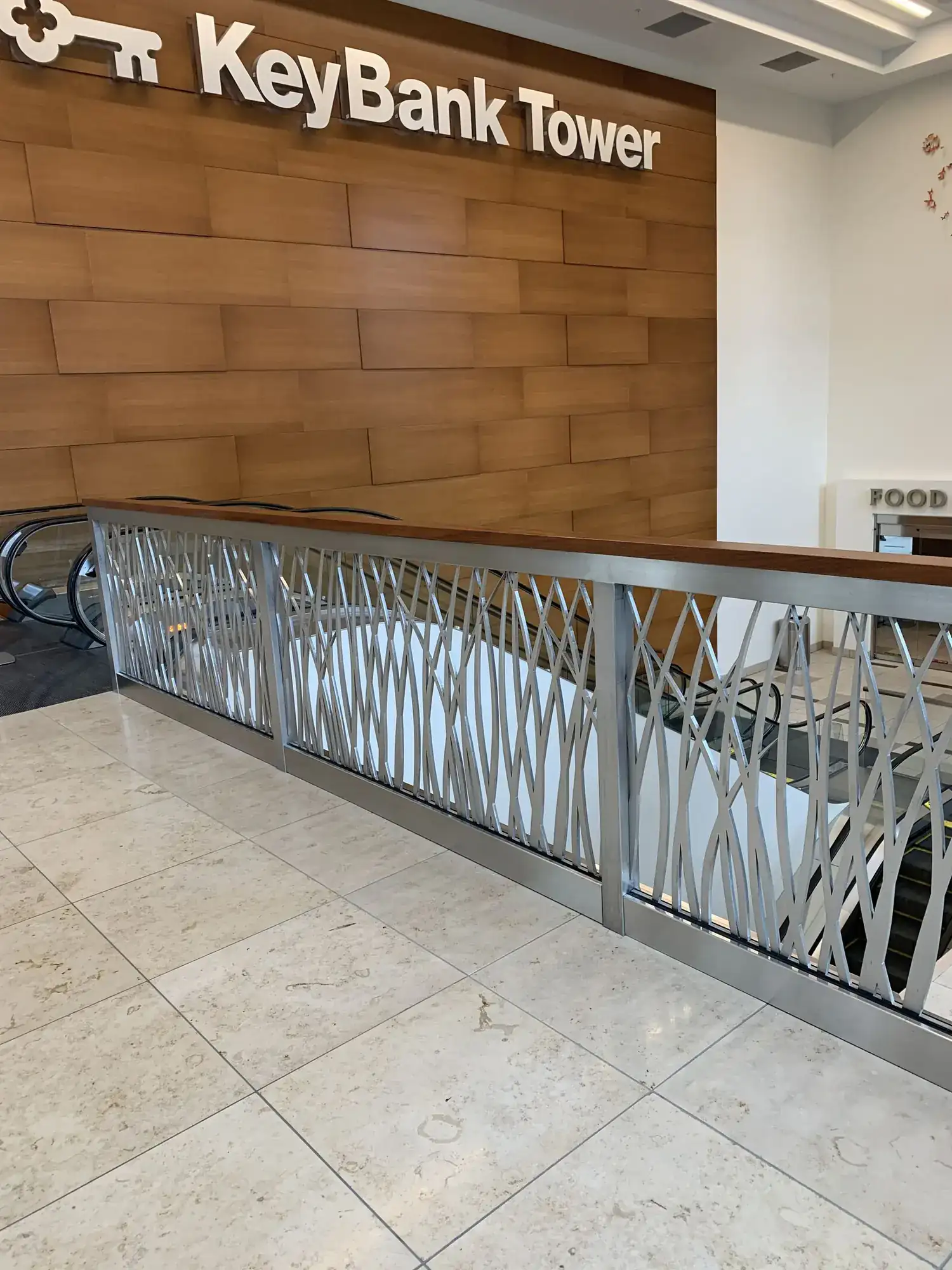 A long run of stainless guardrail with cut-pattern infill along a balcony edge in a tower lobby
