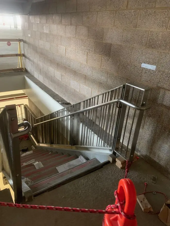 Stainless handrail turning down a stair against a block wall
